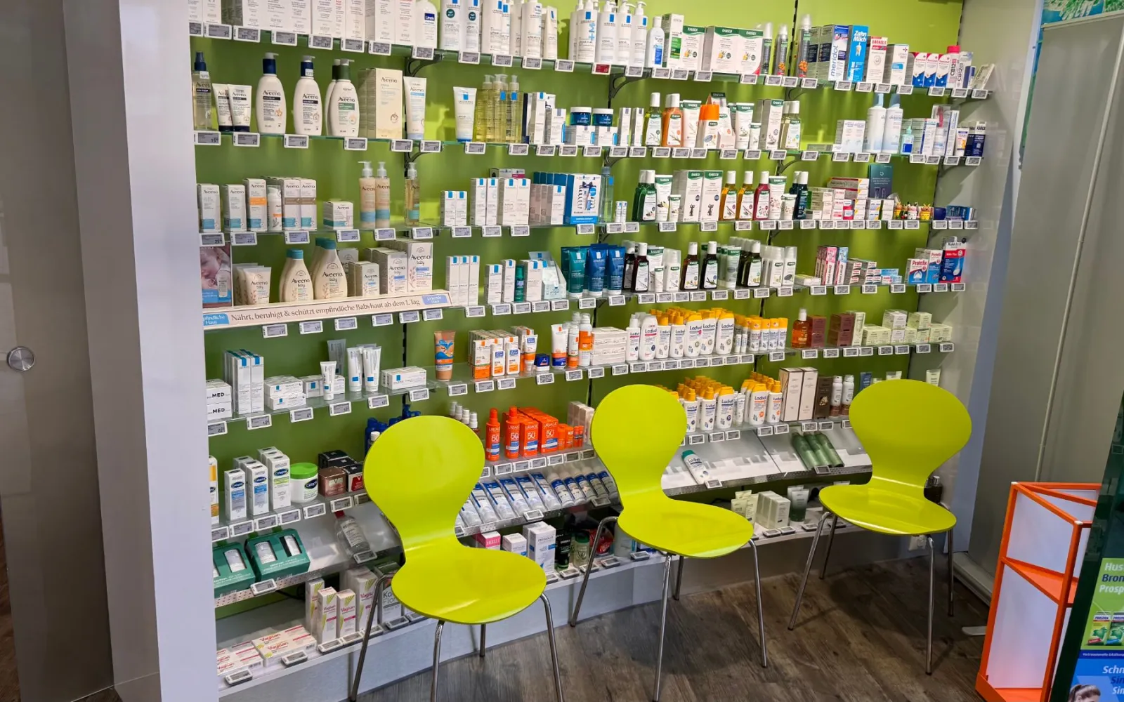 Wartebereich in der Apotheke mit grünen Stühlen, hier bleibst du nach der Impfung noch 15 Minuten